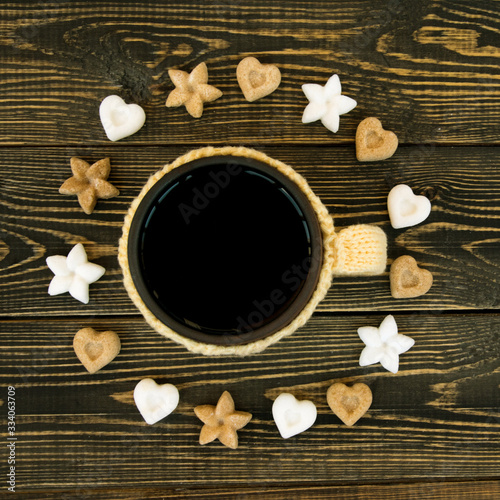 Cup of tea and sugar in form of heart and flower on wooden background