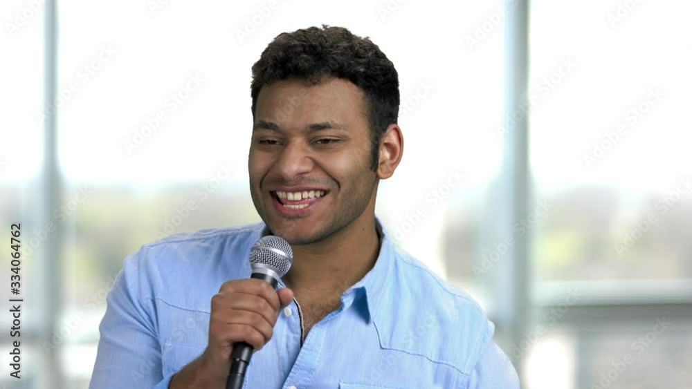 Young positive indian presenter's entertaining people and talking. Speech of happy brown-skinned hindu man with microphone. Young positive indian presenter's entertaining people and talking. Speech of happy brown-skinned hindu man with microphone.