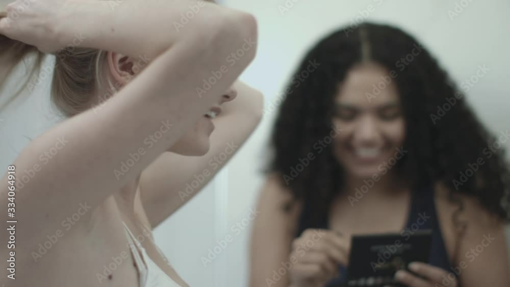 Young female friends applying make up in bathroom Young female friends applying make up in bathroom