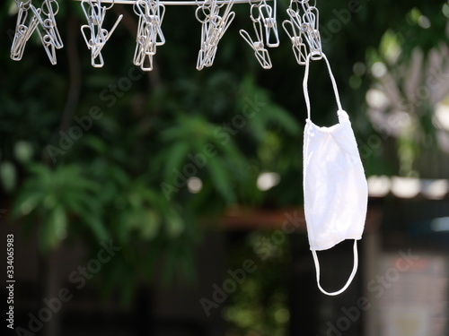 A mask hanging on a  stainless clothespin.