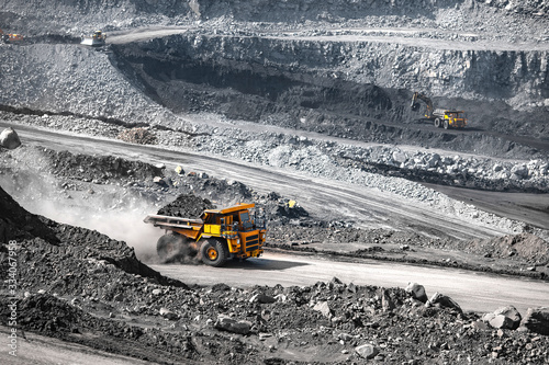 Open pit mine industry. Yellow mining truck for coal moves along dusty quarry road photo