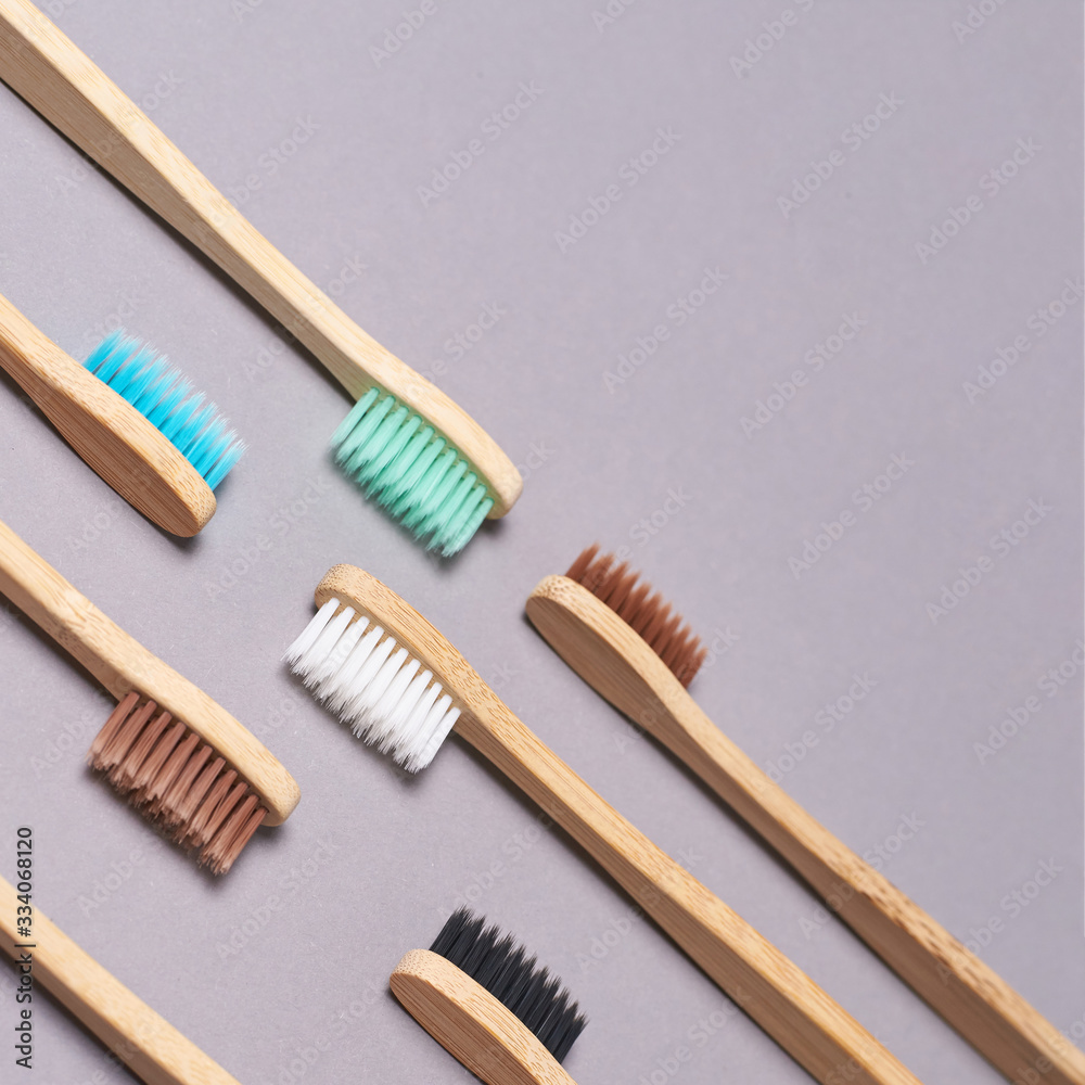 Set of bamboo toothbrushes. Different color. Ecology wood tooth brush group. Grey background. Natural oral hygiene. Dental zero waste protection. Copyspace Set of bamboo toothbrushes. Different color. Ecology wood tooth brush group. Grey background. Natural oral hygiene. Dental zero waste protection. Copyspace