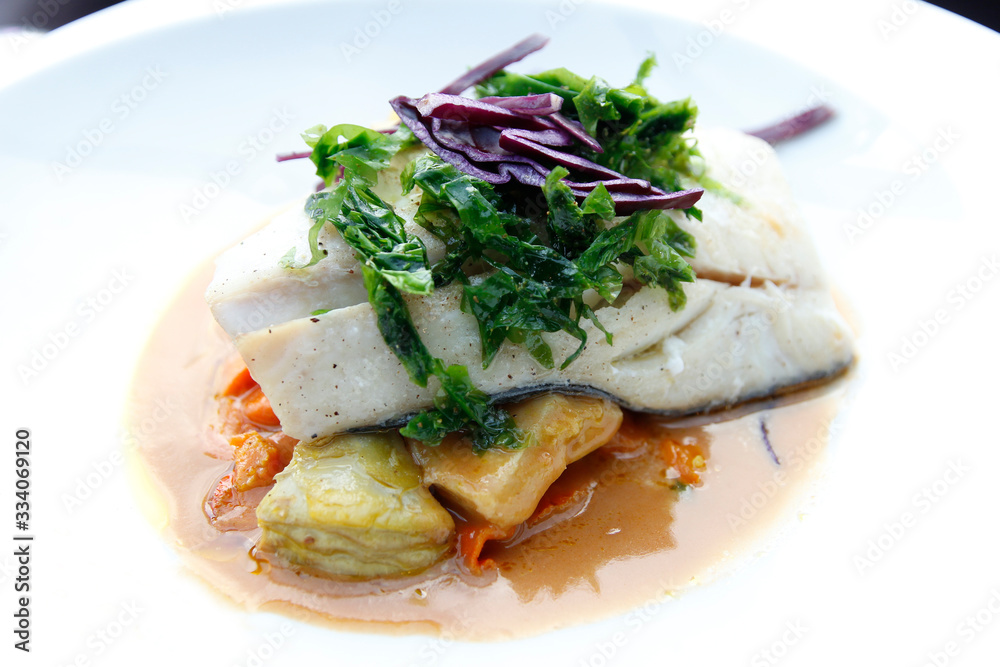 Haddock loin with shellfish juice, roast artichokes and carrots as the main course for dinner in Paris
