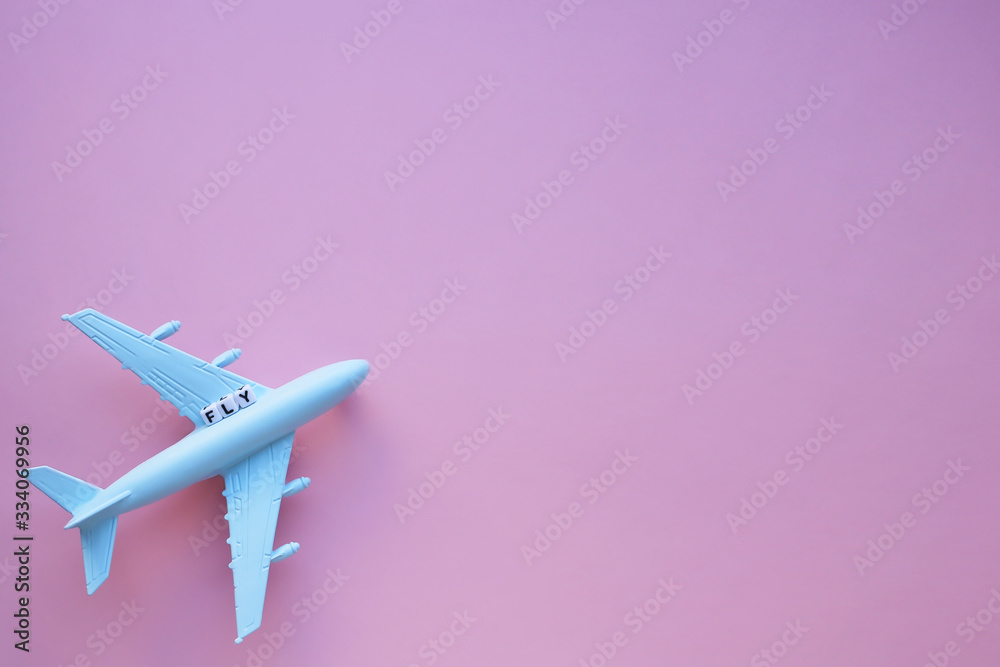 Fototapeta Fly word and airplane model on a pink background. Travel concept