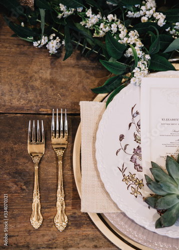 A vignette of a plate setting and gold vintage flatware from a table scape designed for a boho style event with rustic touches