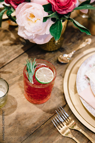 A signature alcoholic cocktail garnished with lime and rosemary on a rustic surface
