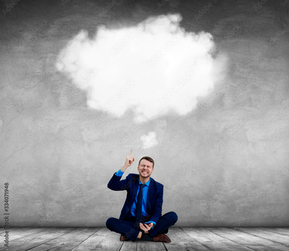 Angry businessman sitting on the floor and pointing on white cloud.
