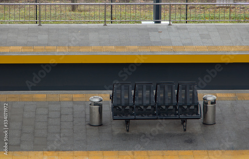 Empty bench on the platform without people. The empty platform with seats at the railway station.