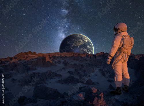 Fototapeta Naklejka Na Ścianę i Meble -  astronaut looking at Earth from the surface of an alien planet