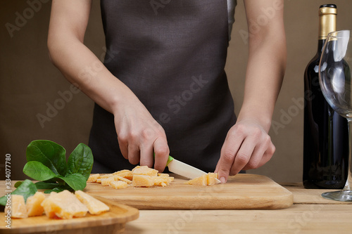 Cooking, food and home concept. Female Hands with knife, wine and cheese