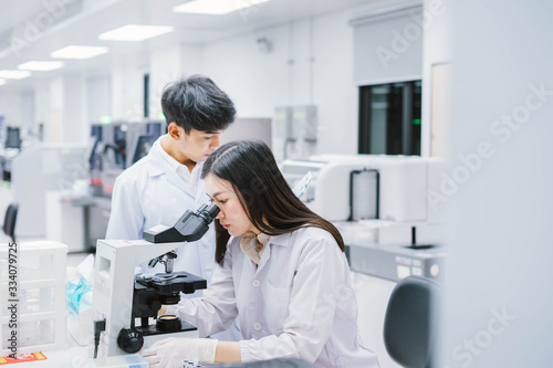 Two  medical  scientist working in Medical laboratory   young female scientist looking at microscope. select focus in young  female scientist