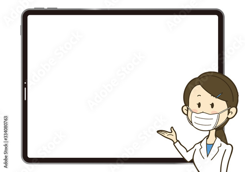 大きなタブレットの画面を背に説明している女性 マスク＆白衣