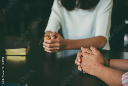 Pray and bible concept.Asian female praying,hope for peace and free from disease,Hand in hand together by woman and Caucasian men,believes and faith in christian religion at church.