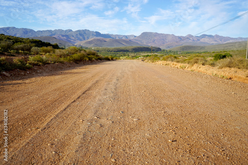 Long open dirt road in mountain landscape Fototapeta