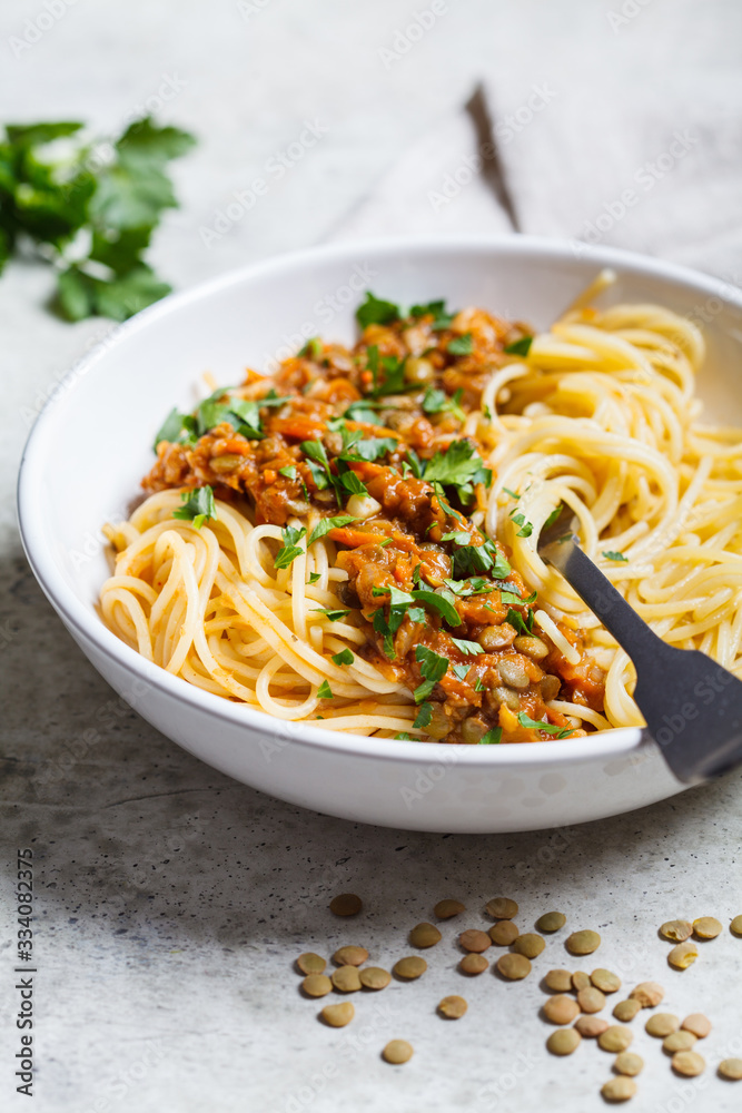 Vegetarian lentils bolognese pasta with parsley in white dish. Healthy vegan food concept.