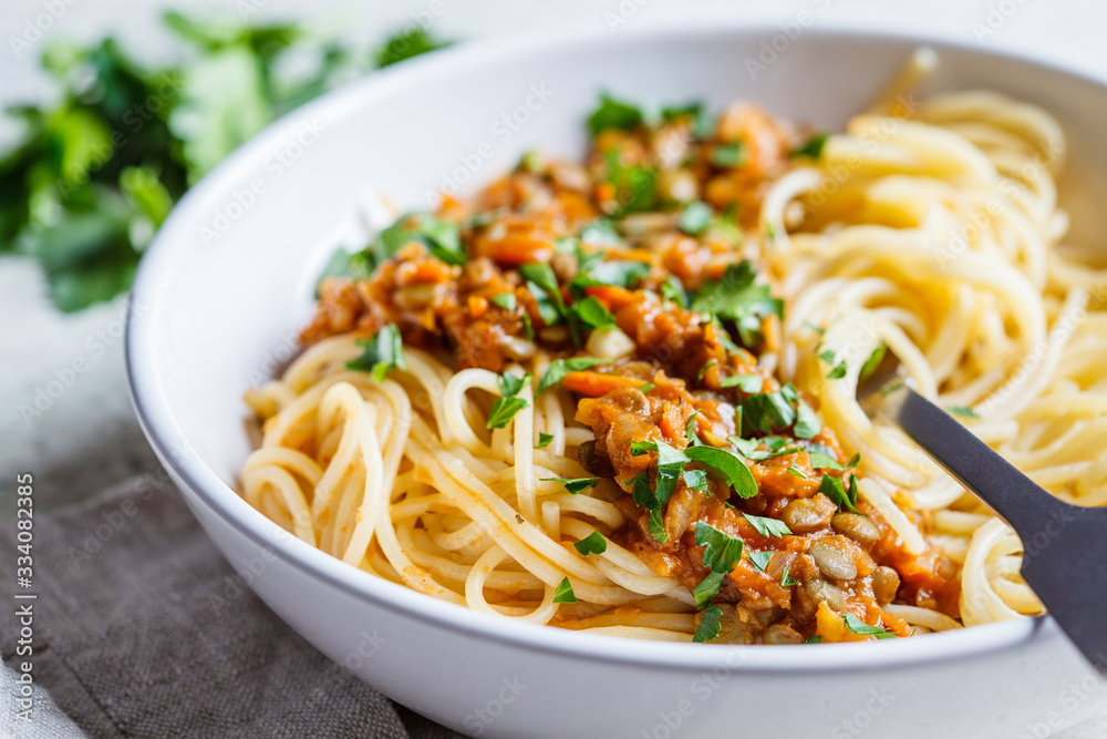 Vegetarian lentils bolognese pasta with parsley in white dish. Healthy vegan food concept. Vegetarian lentils bolognese pasta with parsley in white dish. Healthy vegan food concept.