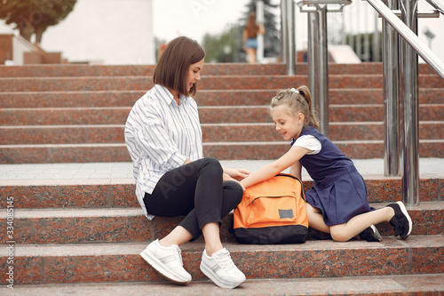 Mother and daughter. Mom puts in the backpack of baby stuff. Family sitting on a stairs.
