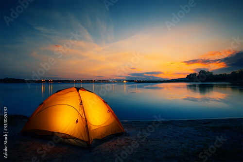 Orange tent on the lake at dusk