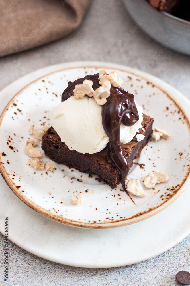 Homemade brownie with scoop of vanilla ice cream, chocolate sauce and nuts. Gray background Homemade brownie with scoop of vanilla ice cream, chocolate sauce and nuts. Gray background