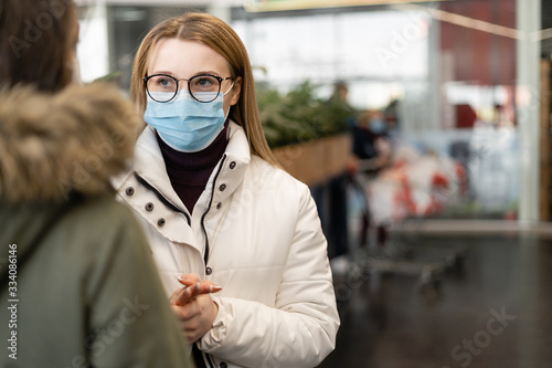 Two women in medical masks and face communicate in a public place. Protection against viruses during a threat. coronavirus covid-19.