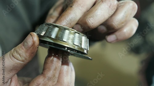 Worker`s hands rotating and cleaning tapered roller bearing in private workshop  photo