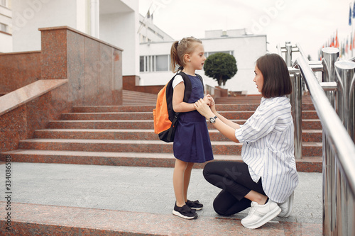 Mother and daughter. Family standing near school. Mom accompanies her child to school