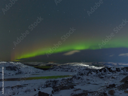 Aurora and stars in the sky .The rocks and ground are covered with snow.Frozen lake.