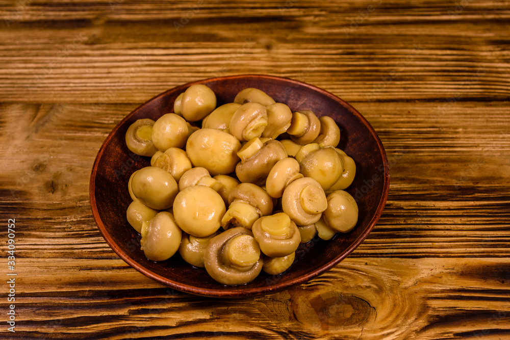 Ceramic plate with canned mushrooms on wooden table Ceramic plate with canned mushrooms on wooden table