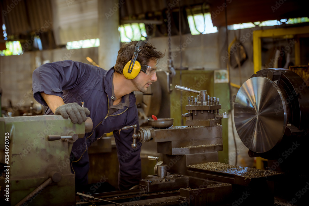 The Industry worker wearing safety uniform used lubricant oil control operating lathe grinding machine working in industry factory. The Industry worker wearing safety uniform used lubricant oil control operating lathe grinding machine working in industry factory.