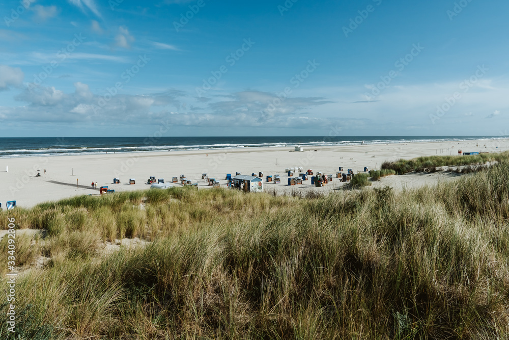 Wide beach landscape with colorful beach chairs on a sunny day at the beach of Juist, Germany