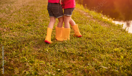 Twin sisters in rubber boots walking in park