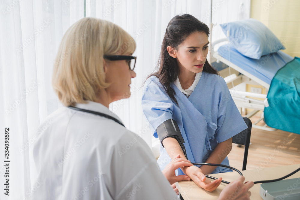 Senior woman doctor checking young female patient blood pressure. Senior woman doctor checking young female patient blood pressure.