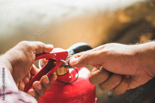 Close up hand Fireman using fire extinguisher fighting. Hand pulling pin of fire extinguisher photo