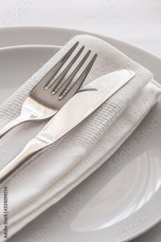 Silver fork and knife with white linen napkin on the plate. Restaurant dinning concept. Close up of detail