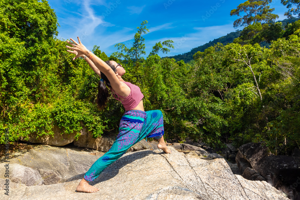 Naklejka premium Asian Thai woman practicing yoga on the top of a rock in Koh Phangan island, Thailand