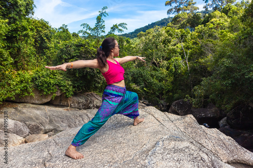 Asian Thai woman practicing yoga on the top of a rock in Koh Phangan island, Thailand