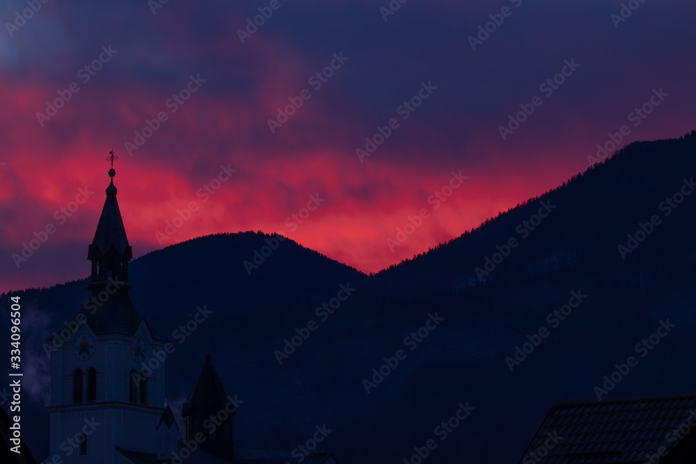Pink sunlit sky over church in Bohinjska Bistrica