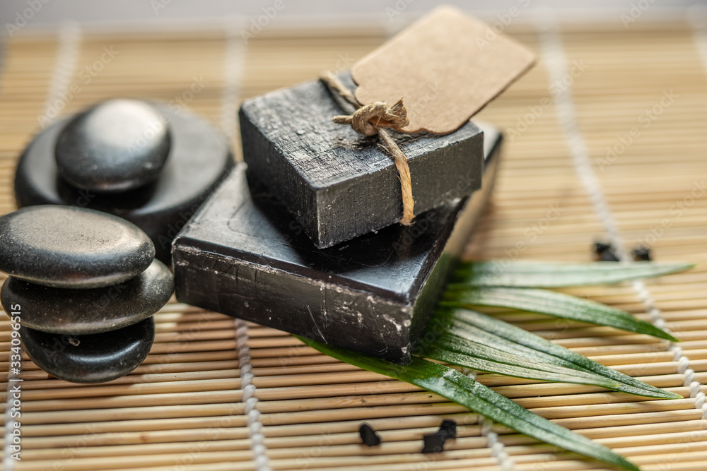 bar block of black carbon charcoal coal soap on a bamboo background with lava stones spa concept bar block of black carbon charcoal coal soap on a bamboo background with lava stones spa concept
