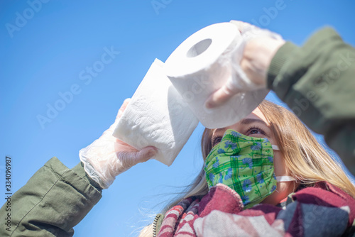 junge Frau mit Mundschutz und Toillettenpapier in der Stadt photo