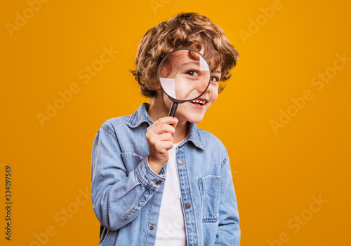 Cheerful boy with magnifying glass looking at camera