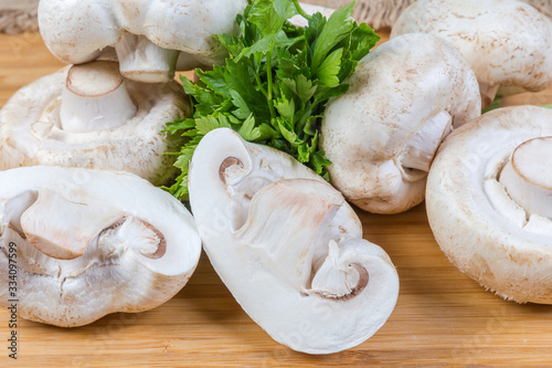 Background of uncooked button mushrooms and parsley on wooden surface