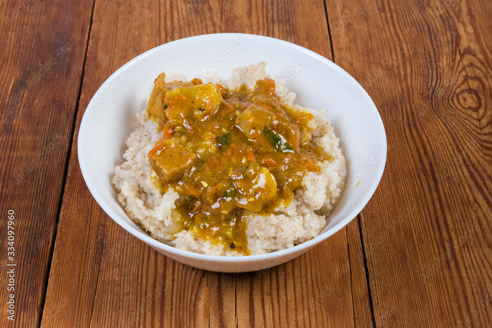 Barley porridge with meat sauce in bowl on rustic table