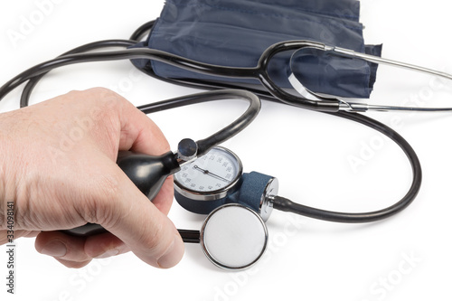 Rubber bulb of sphygmomanometer in male hand, stethoscope and sphygmomanometer