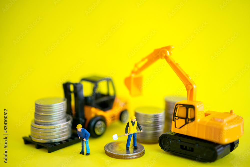 Miniature figure of Worker with  excavator and forklifts and stack of coins with yellow background. Making money and profit in business and finance