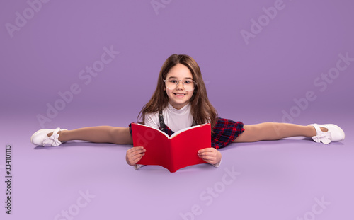 Flexible schoolgirl doing homework and smiling