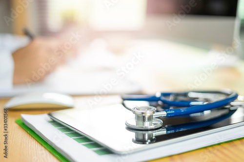  medical stethoscope lying on tablet and clipboard with documentation of health insurance in form or a contract, blur background of a doctor signing a form contract and a computer device