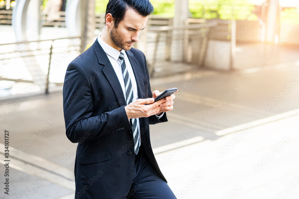 portrait of a caucasian business man using his phone for internet; messaging; call; texting and socializing; handsome looking and wearing a suit and tie within an urban city structure in background portrait of a caucasian business man using his phone for internet; messaging; call; texting and socializing; handsome looking and wearing a suit and tie within an urban city structure in background