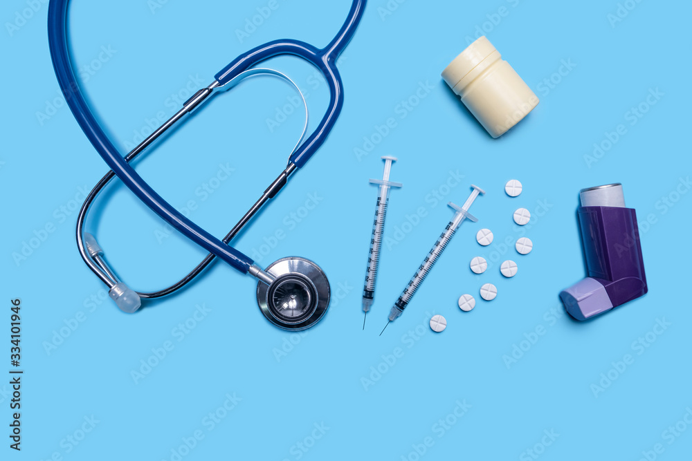 layout of health and medical care testing for checkup on patient, with inhaler, stethoscope, syringe, pills container for diagnosis and testing on ill patients wellness, on blue flat lay background layout of health and medical care testing for checkup on patient, with inhaler, stethoscope, syringe, pills container for diagnosis and testing on ill patients wellness, on blue flat lay background