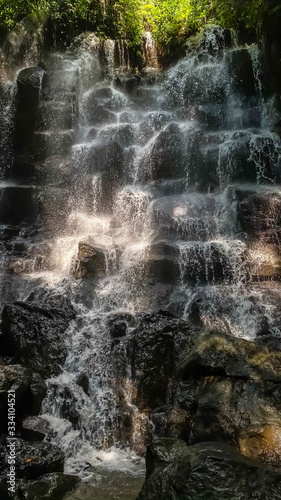 Waterfall in Bali Kanto Lampo. Vertical background