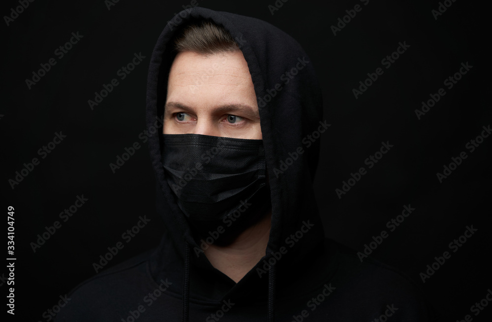 Young man wearing face mask over black background, close-up Young man wearing face mask over black background, close-up